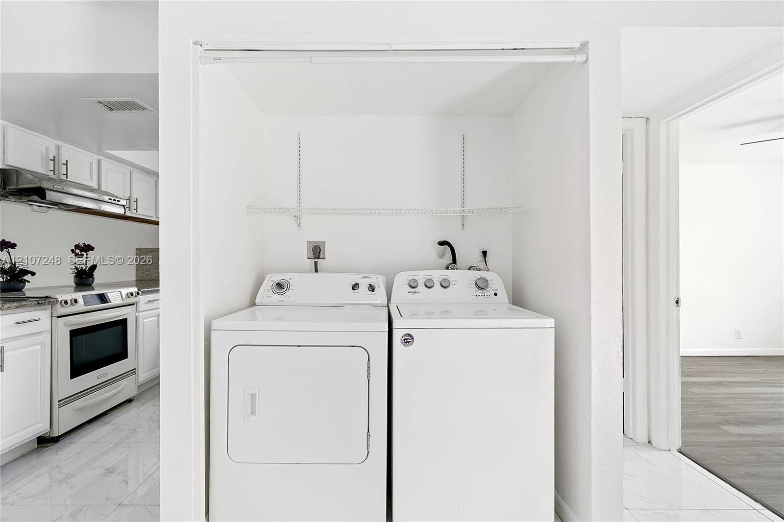 9983 W Atlantic Boulevard, #9983, Coral Springs, Coral Springs, FL 33071 Laundry alcove featuring white-finished cabinetry, adjustable metal shelving, and white tile flooring