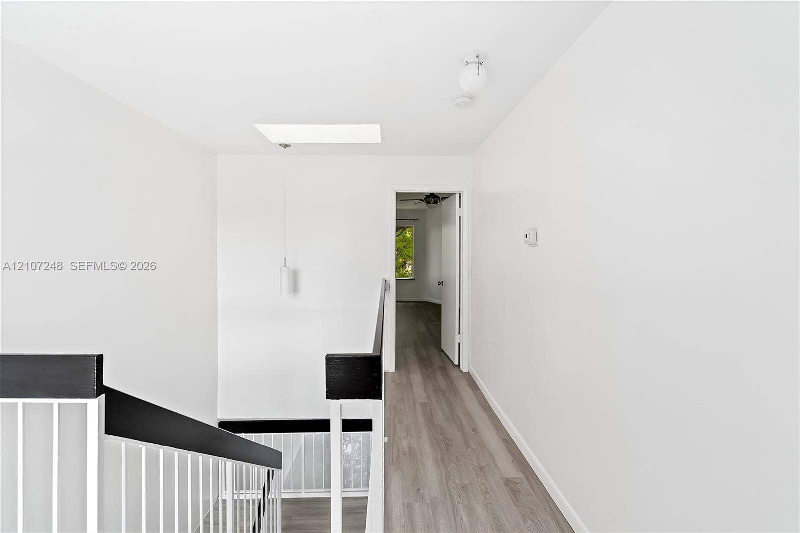 9983 W Atlantic Boulevard, #9983, Coral Springs, Coral Springs, FL 33071 Stairwell featuring a metal handrail, skylight, pendant lighting, and wood-finish flooring