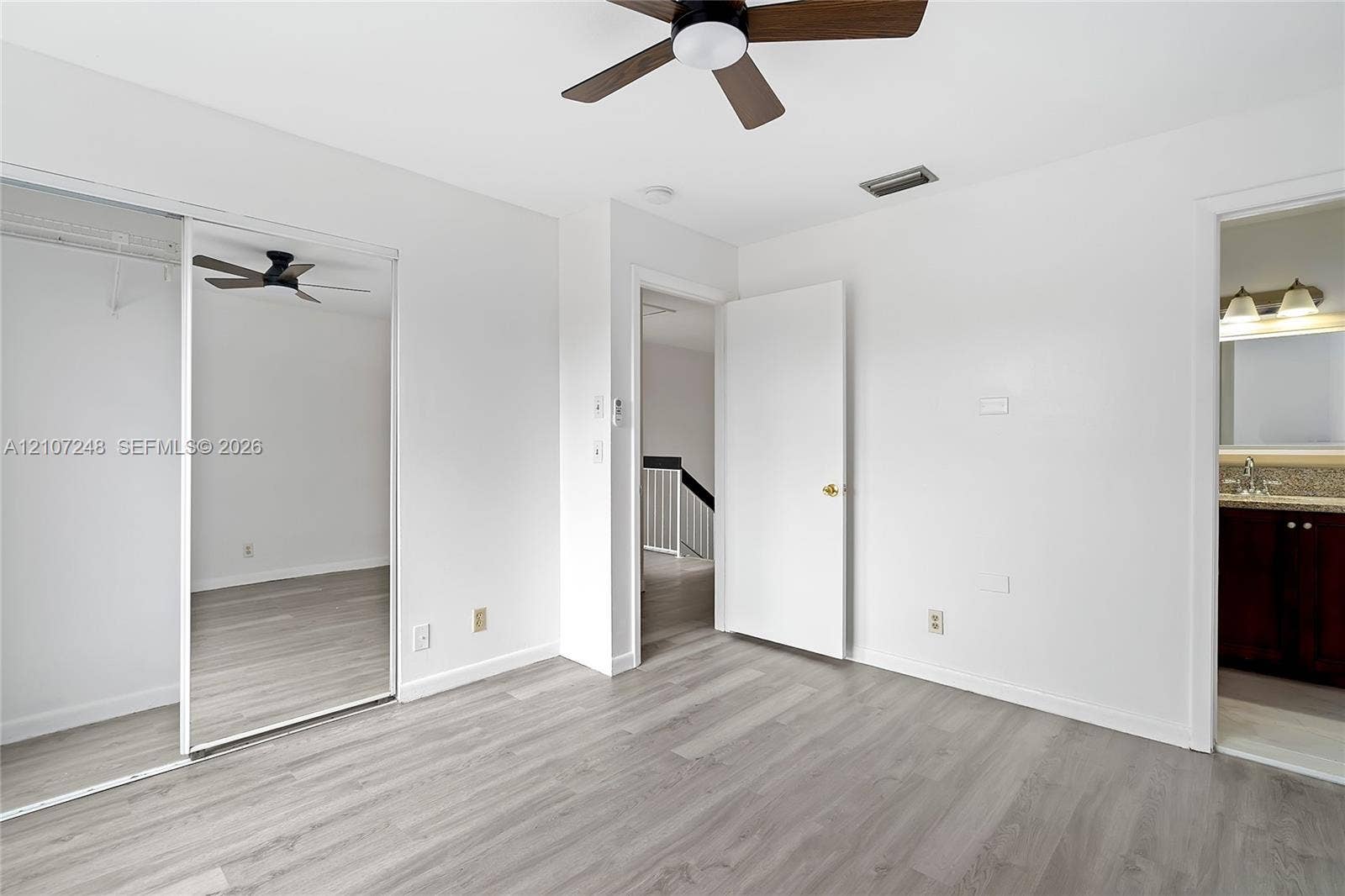 9983 W Atlantic Boulevard, #9983, Coral Springs, Coral Springs, FL 33071 Room featuring wood-finish flooring, a mirrored sliding-door closet, and a ceiling-mounted fan with integrated lighting