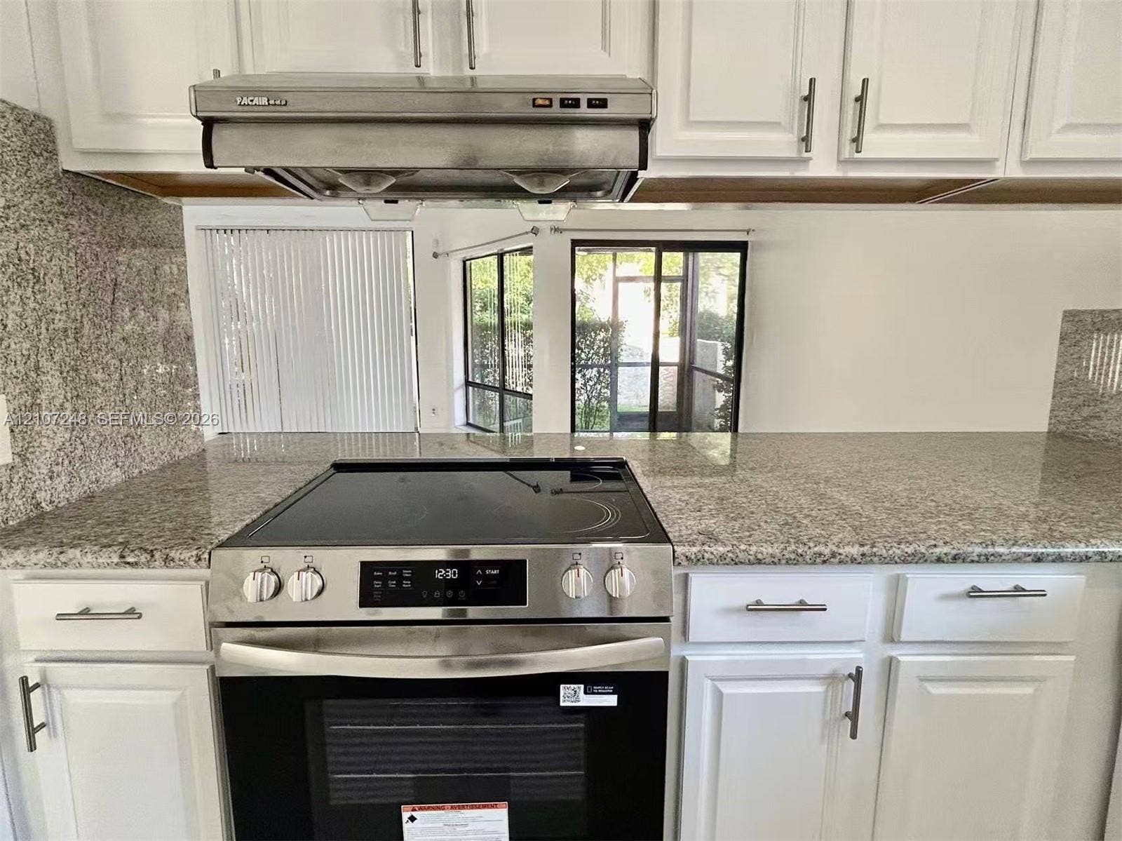 9983 W Atlantic Boulevard, #9983, Coral Springs, Coral Springs, FL 33071 Kitchen featuring white shaker-style cabinetry, stainless steel electric slide-in range, stone-composite countertops, and an integrated stainless steel range hood