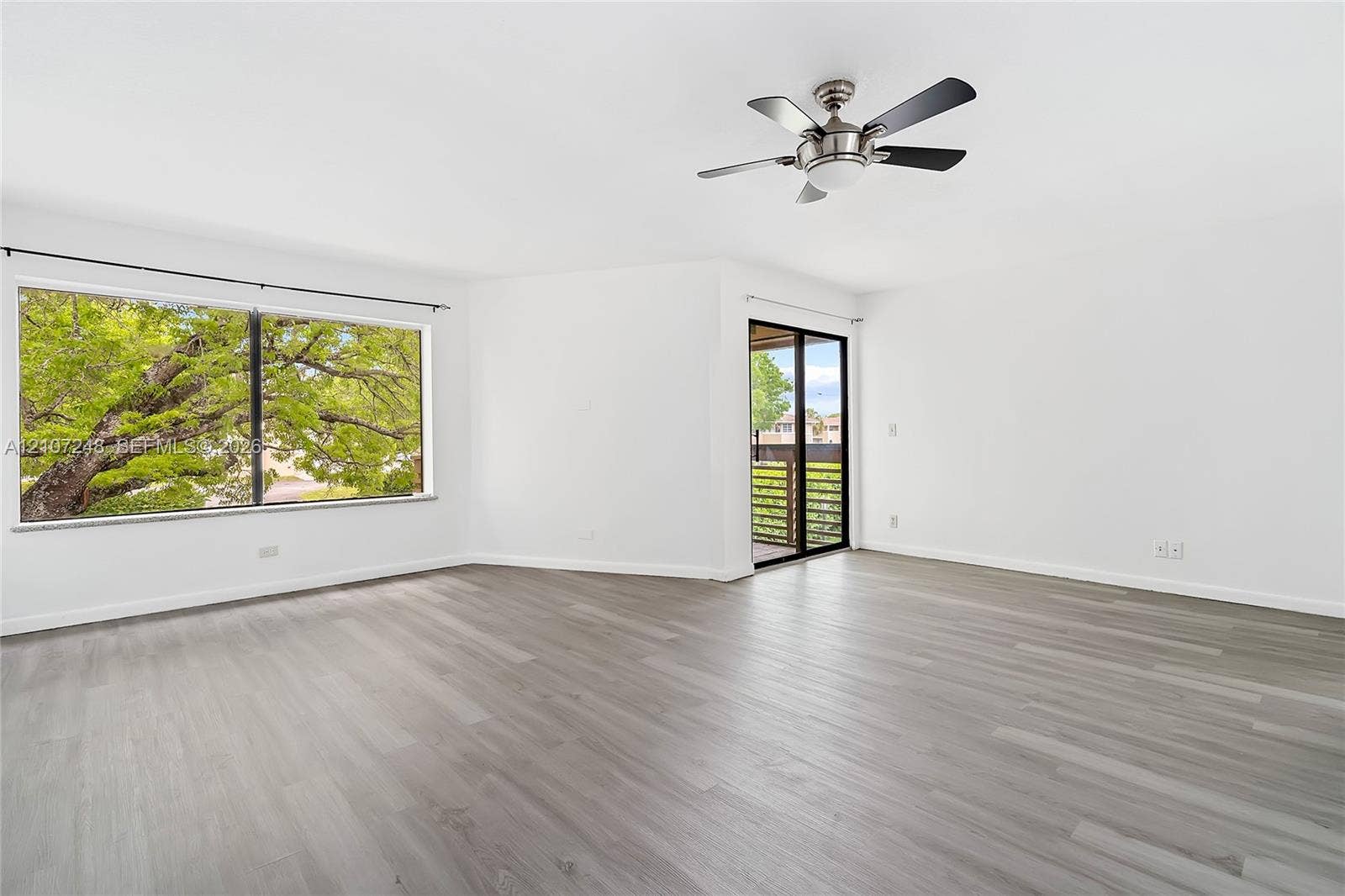 9983 W Atlantic Boulevard, #9983, Coral Springs, Coral Springs, FL 33071 Open floor plan featuring wood-finish flooring, a ceiling fan with integrated lighting, a large picture window, and glass sliding doors