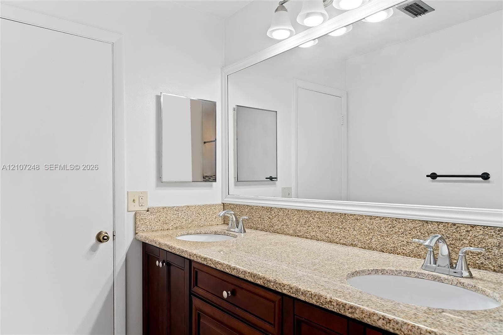 9983 W Atlantic Boulevard, #9983, Coral Springs, Coral Springs, FL 33071 Dual-sink vanity with stone-finish countertop, dark wood cabinetry, and large full-width mirror with four-light fixture