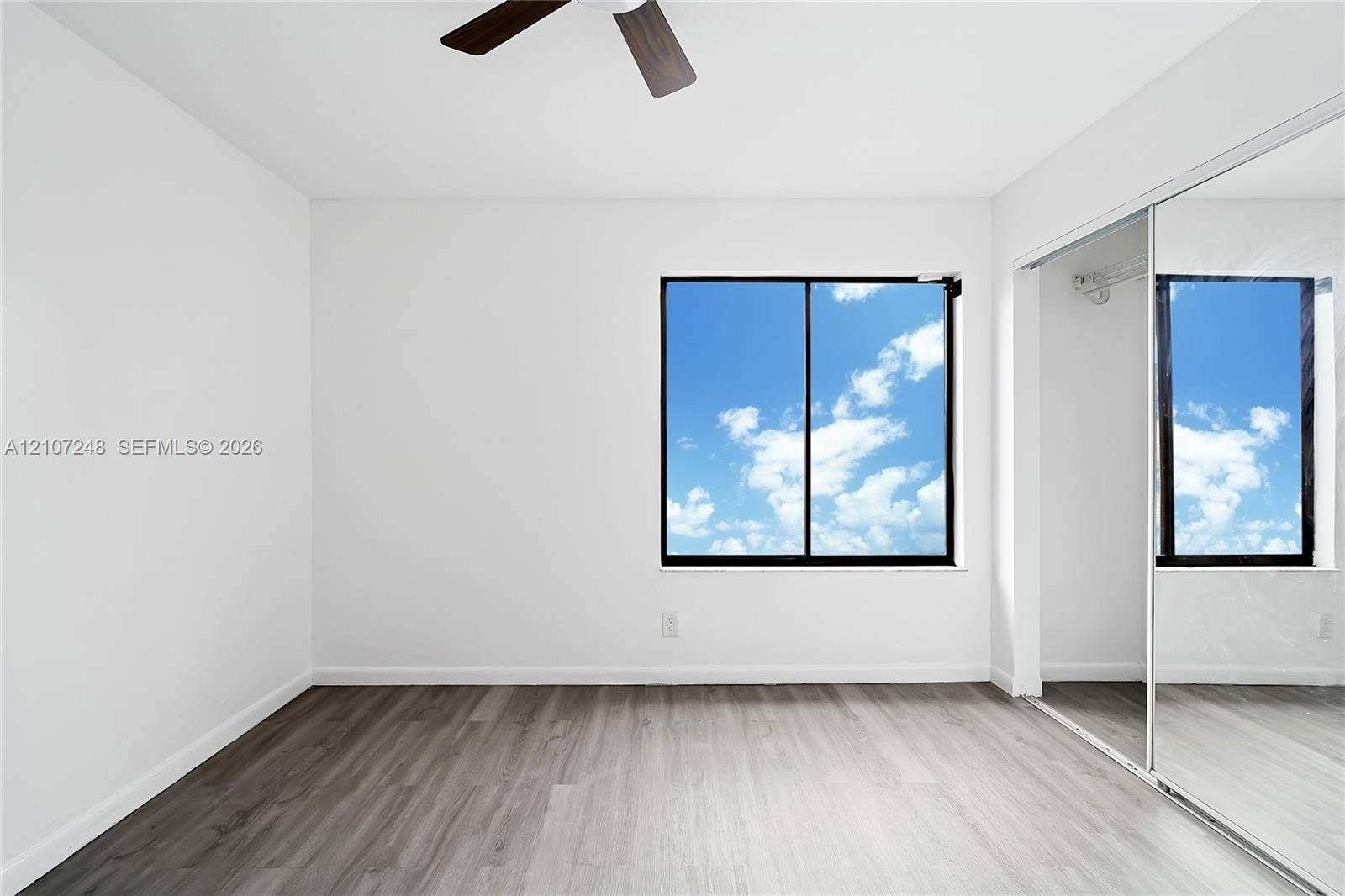 9983 W Atlantic Boulevard, #9983, Coral Springs, Coral Springs, FL 33071 Neutral-toned wood-finish flooring, sliding mirror-panel closet doors, single-pane window, and overhead ceiling fan