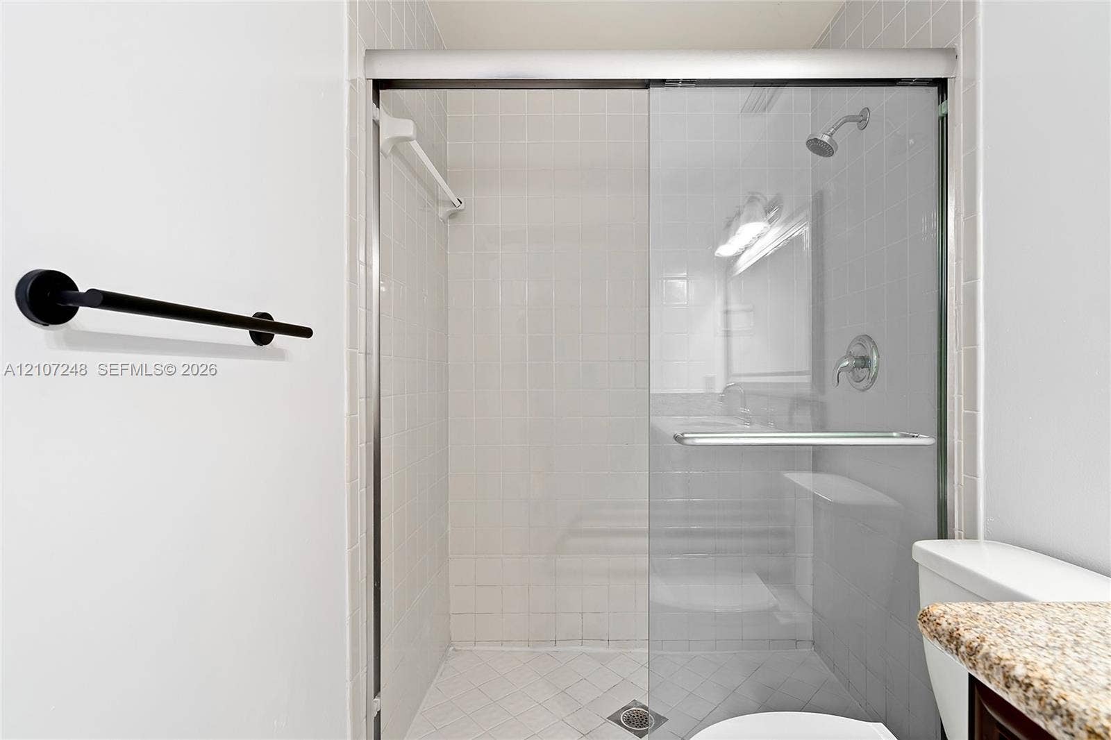 9983 W Atlantic Boulevard, #9983, Coral Springs, Coral Springs, FL 33071 Shower enclosure featuring white wall tiling, sliding glass door, fixed shower head, and matte black towel bar