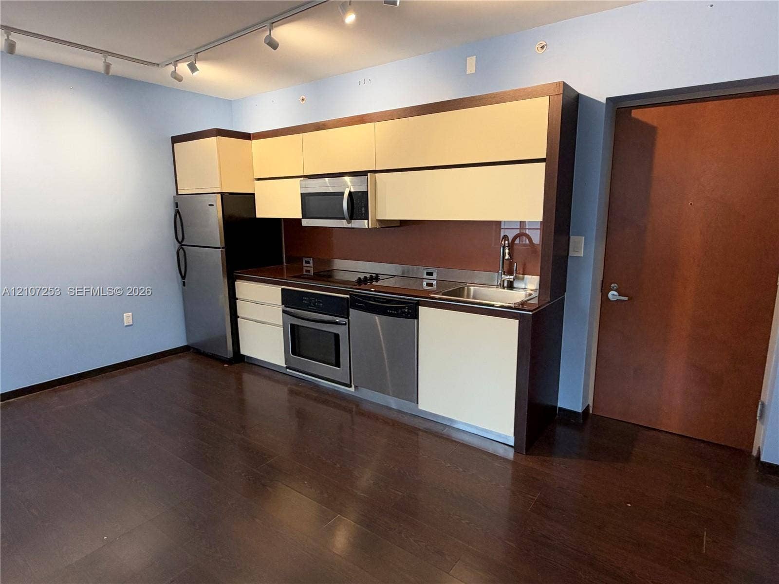 435 21st Street, #316, Miami Beach, Miami Beach, FL 33139 Kitchen featuring stainless steel appliances, flat-panel cabinetry, a solid-surface backsplash, and wood-finish flooring with ceiling-mounted track lighting
