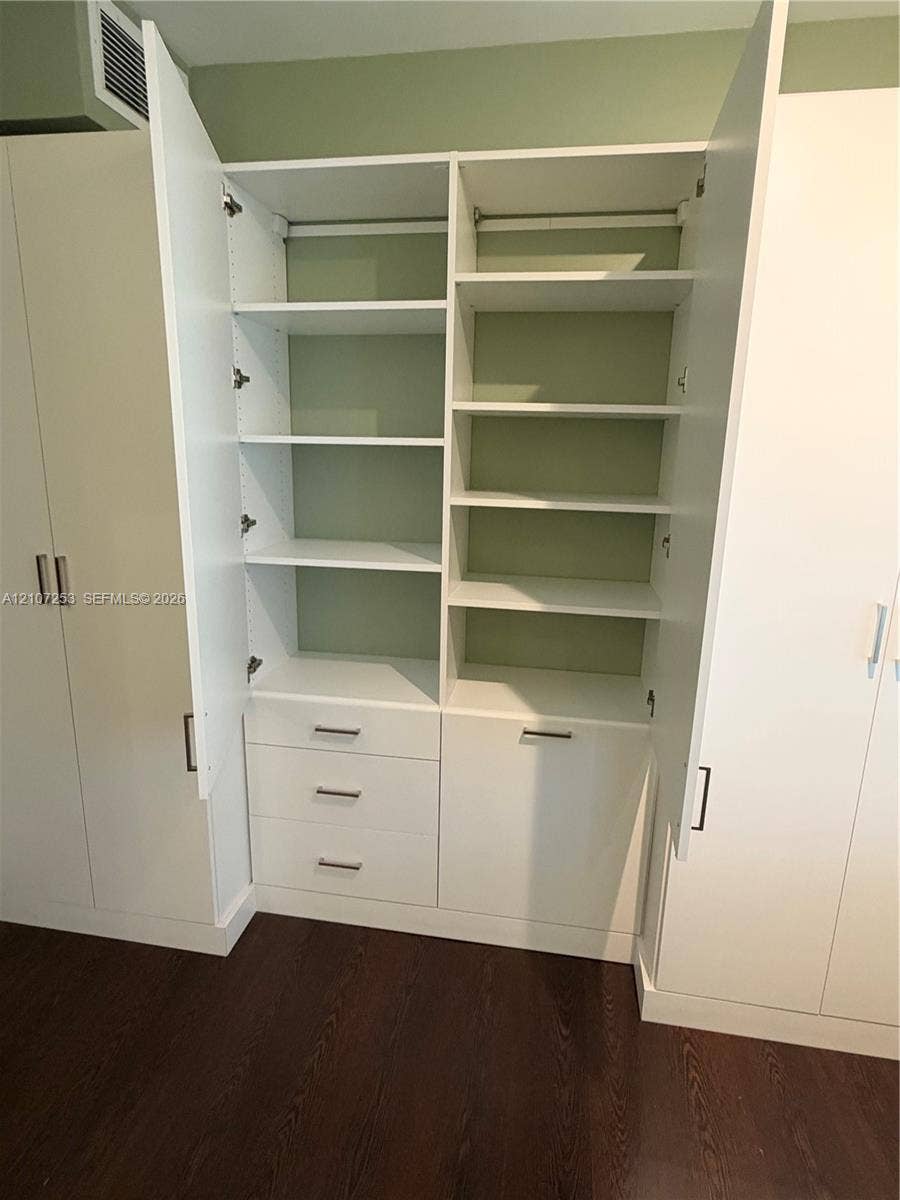 435 21st Street, #316, Miami Beach, Miami Beach, FL 33139 Custom built-in white cabinetry featuring adjustable shelving, integrated storage drawers, hanging rods, and sleek metallic hardware over wood-finish flooring
