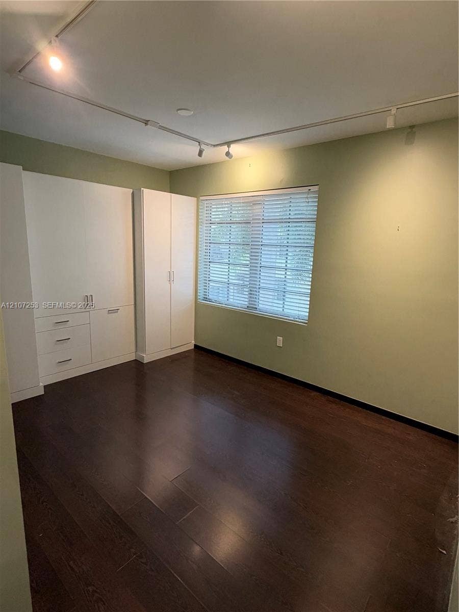 435 21st Street, #316, Miami Beach, Miami Beach, FL 33139 Built-in white cabinetry featuring integrated drawer and cabinet storage, dark wood-finish flooring, adjustable track lighting, and horizontal window blinds