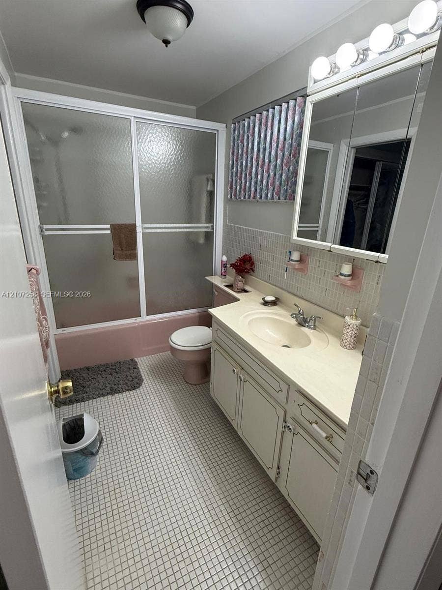 215 SE 3rd Avenue, #102D, Hallandale Beach, FL 33009 Bathroom featuring a built-in vanity with an integrated countertop and sink, mirrored medicine cabinet, mosaic tile wall accents, and a tiled floor