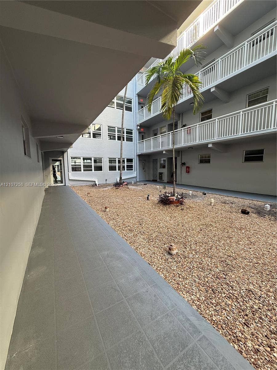 215 SE 3rd Avenue, #102D, Hallandale Beach, FL 33009 Solid door featuring a geometric diamond-shaped panel, chrome finish lever handle, and a decorative metal door knocker, set against red ceramic floor tiling