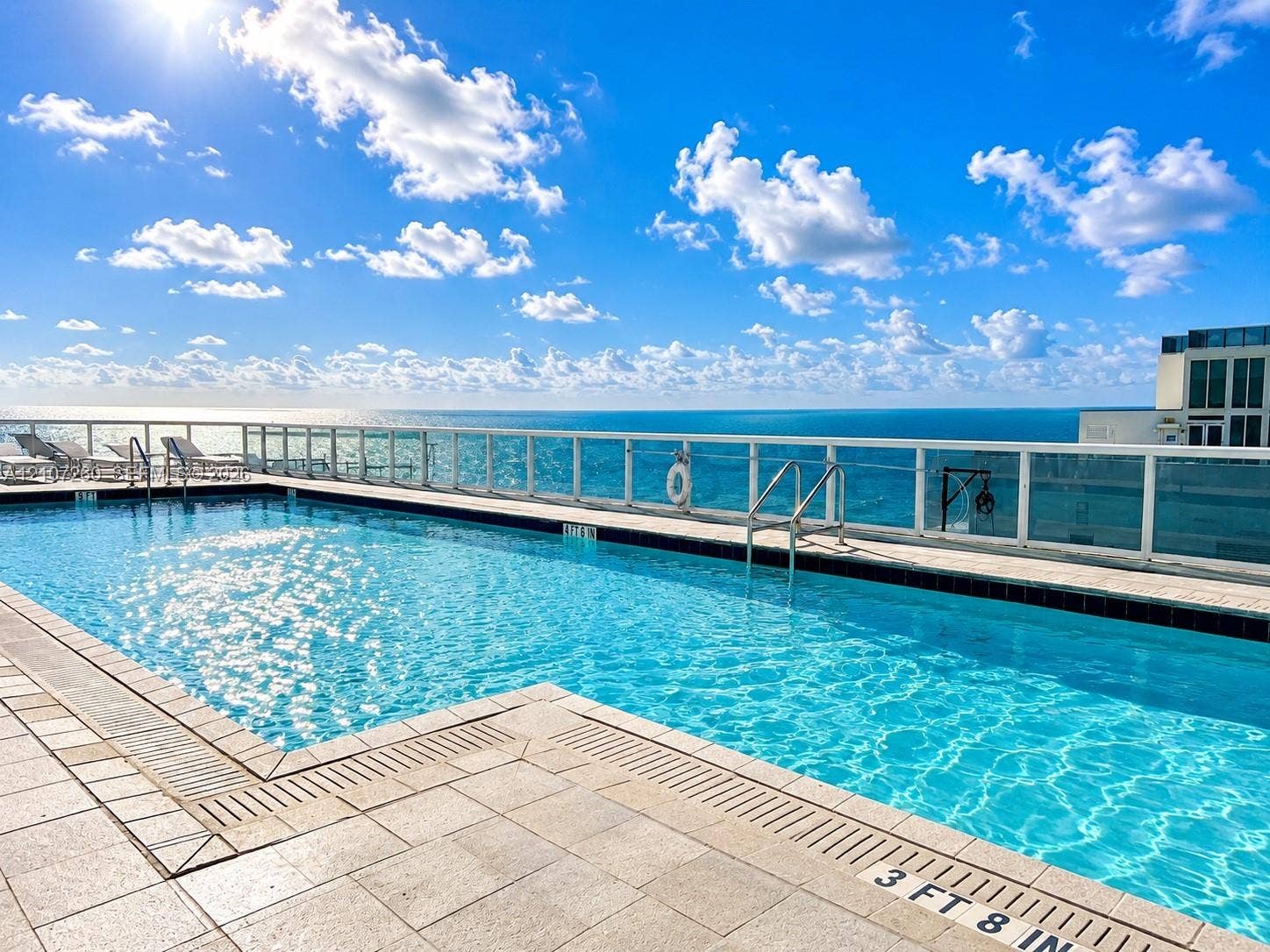 16001 Collins Avenue, #1605, Sunny Isles Beach, FL 33160 Elevated swimming pool featuring stone-tile decking, metal safety railing, and integrated pool drainage