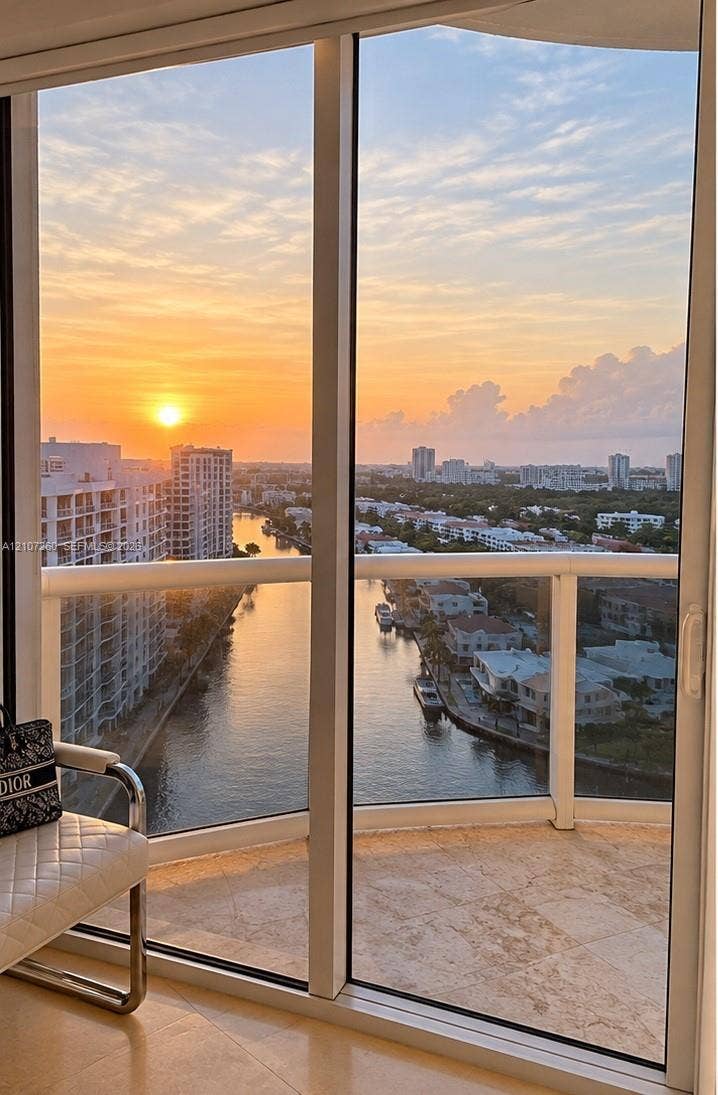 16001 Collins Avenue, #1605, Sunny Isles Beach, FL 33160 Floor-to-ceiling glass sliding doors, wrap-around balcony, stone flooring, and expansive water and skyline scenery