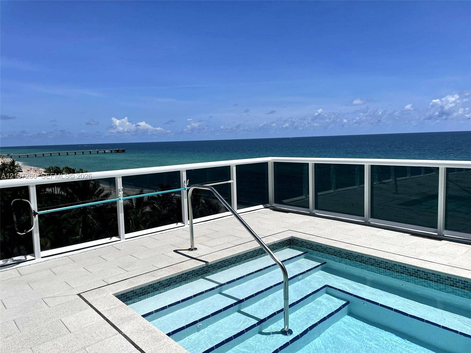 16001 Collins Avenue, #1605, Sunny Isles Beach, FL 33160 Rooftop terrace featuring a tiled deck, built-in spa with integrated steps, stainless steel handrail, and white frame glass railing