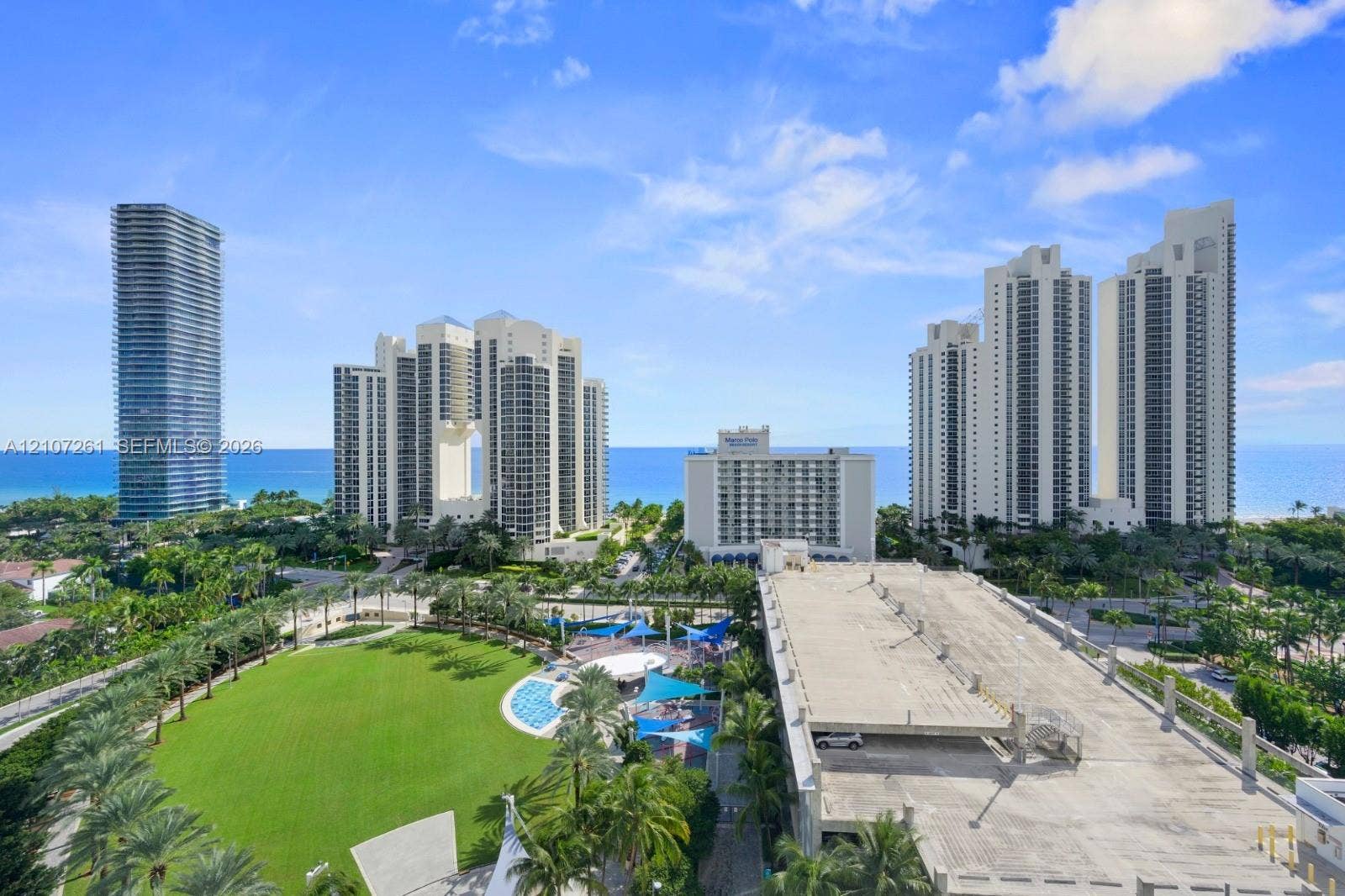 19370 Collins Avenue, #1601, Sunny Isles Beach, Sunny Isles Beach, FL 33160 Aerial perspective featuring expansive green space, mature palm trees, multi-story high-rise architecture, and coastal proximity