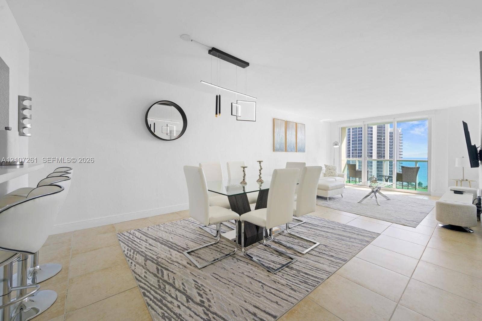19370 Collins Avenue, #1601, Sunny Isles Beach, Sunny Isles Beach, FL 33160 Open-concept interior featuring light-toned tile flooring, built-in breakfast bar, modern geometric pendant lighting, and floor-to-ceiling glass sliding doors