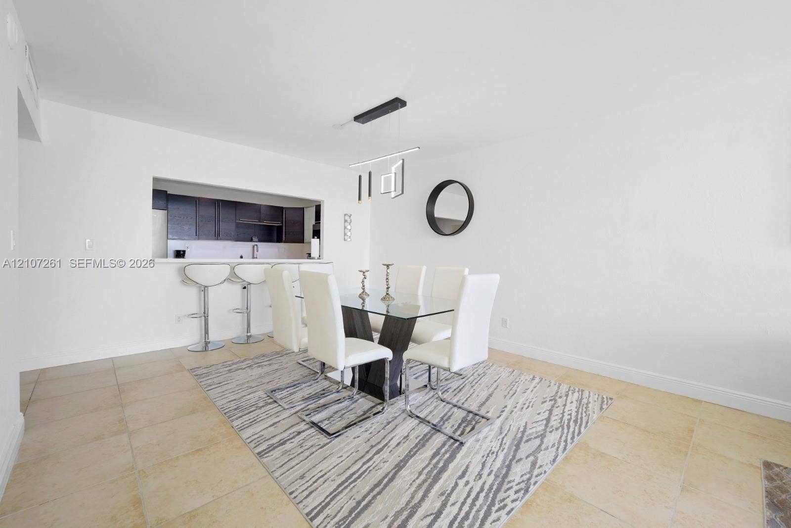 19370 Collins Avenue, #1601, Sunny Isles Beach, Sunny Isles Beach, FL 33160 Dining area featuring large-format tile flooring, a pass-through opening to the kitchen, a breakfast bar, and a modern linear pendant light fixture