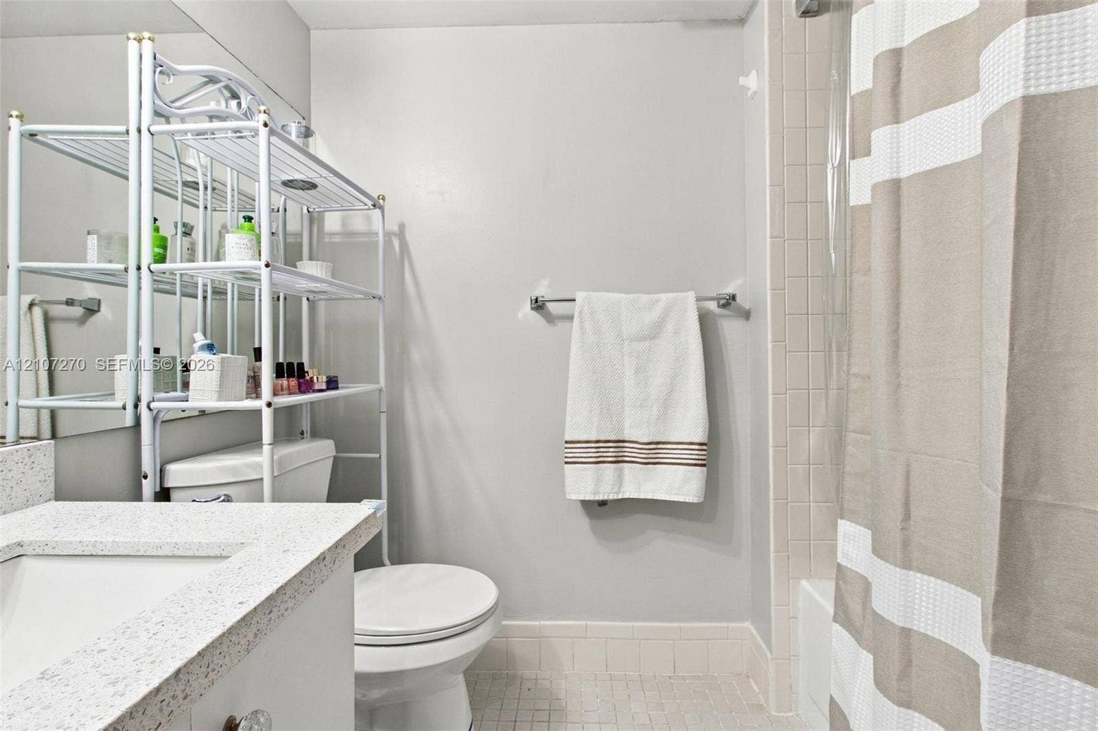 12501 SW 14th Street, #311R, Pembroke Pines, FL 33027 Bathroom featuring a vanity with a speckled countertop and integrated rectangular sink, wall-spanning mirror, ceramic tile shower surround, and tile flooring