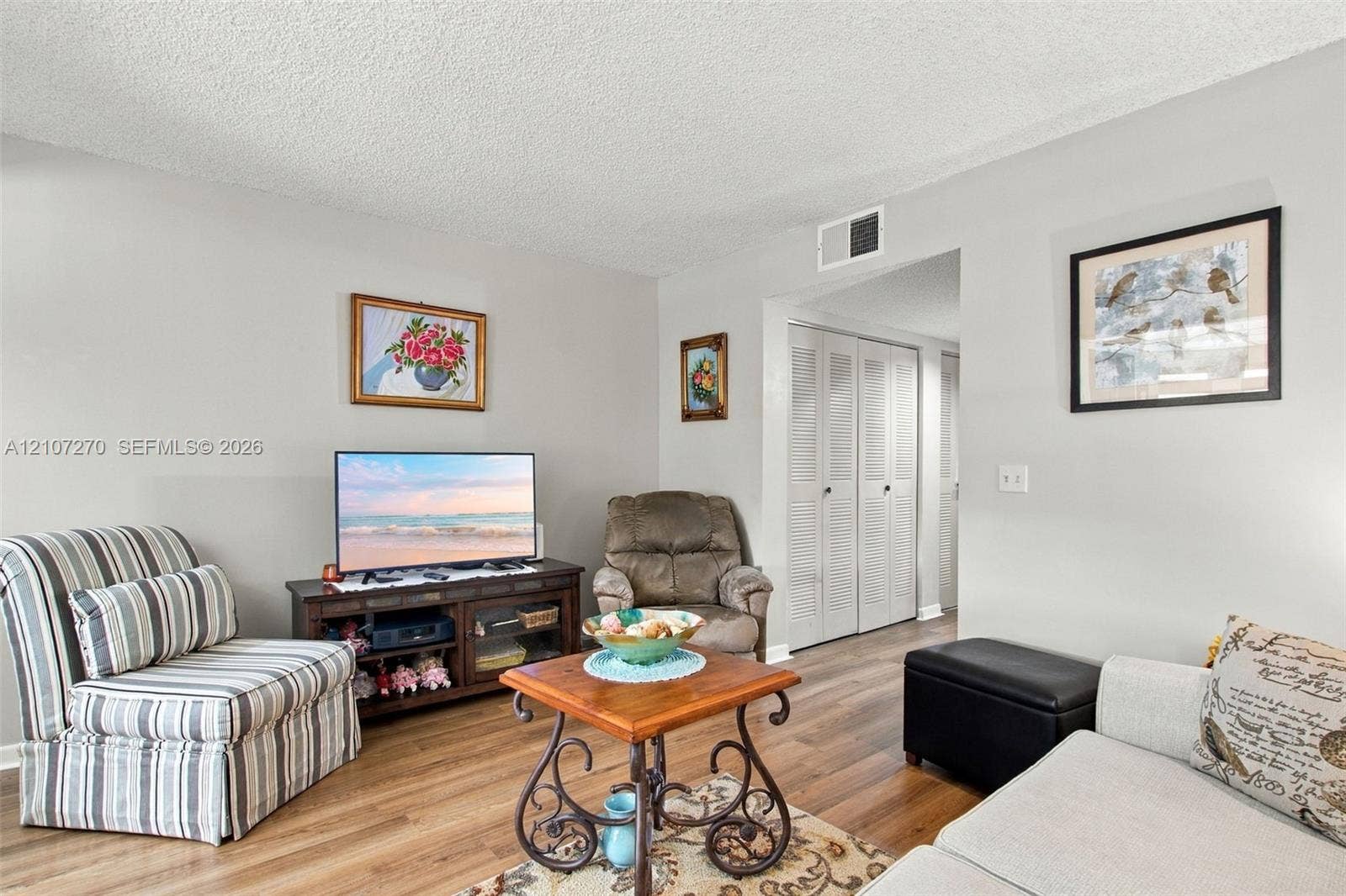 12501 SW 14th Street, #311R, Pembroke Pines, FL 33027 Living area featuring wood-finish flooring and double bi-fold closet doors with louvered panels
