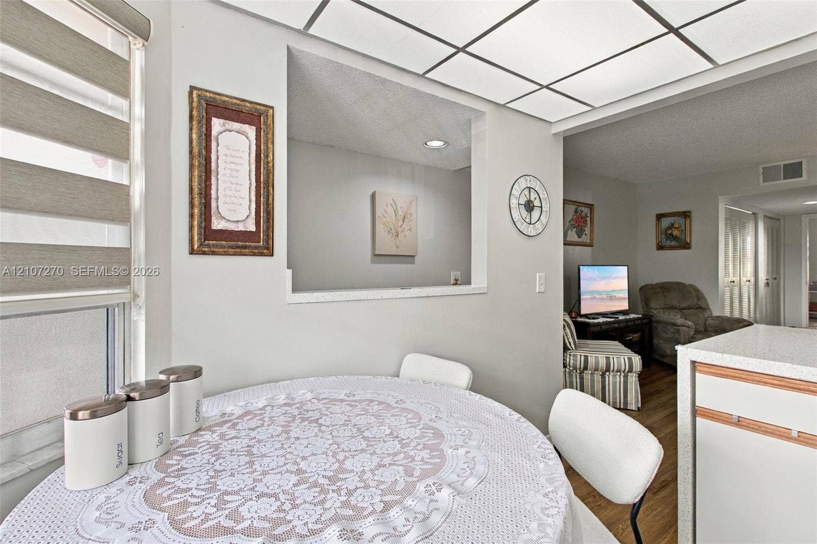 12501 SW 14th Street, #311R, Pembroke Pines, FL 33027 Pass-through window between rooms featuring a recessed opening, tray ceiling with inset panel lighting, tiered window shades, and solid surface countertop