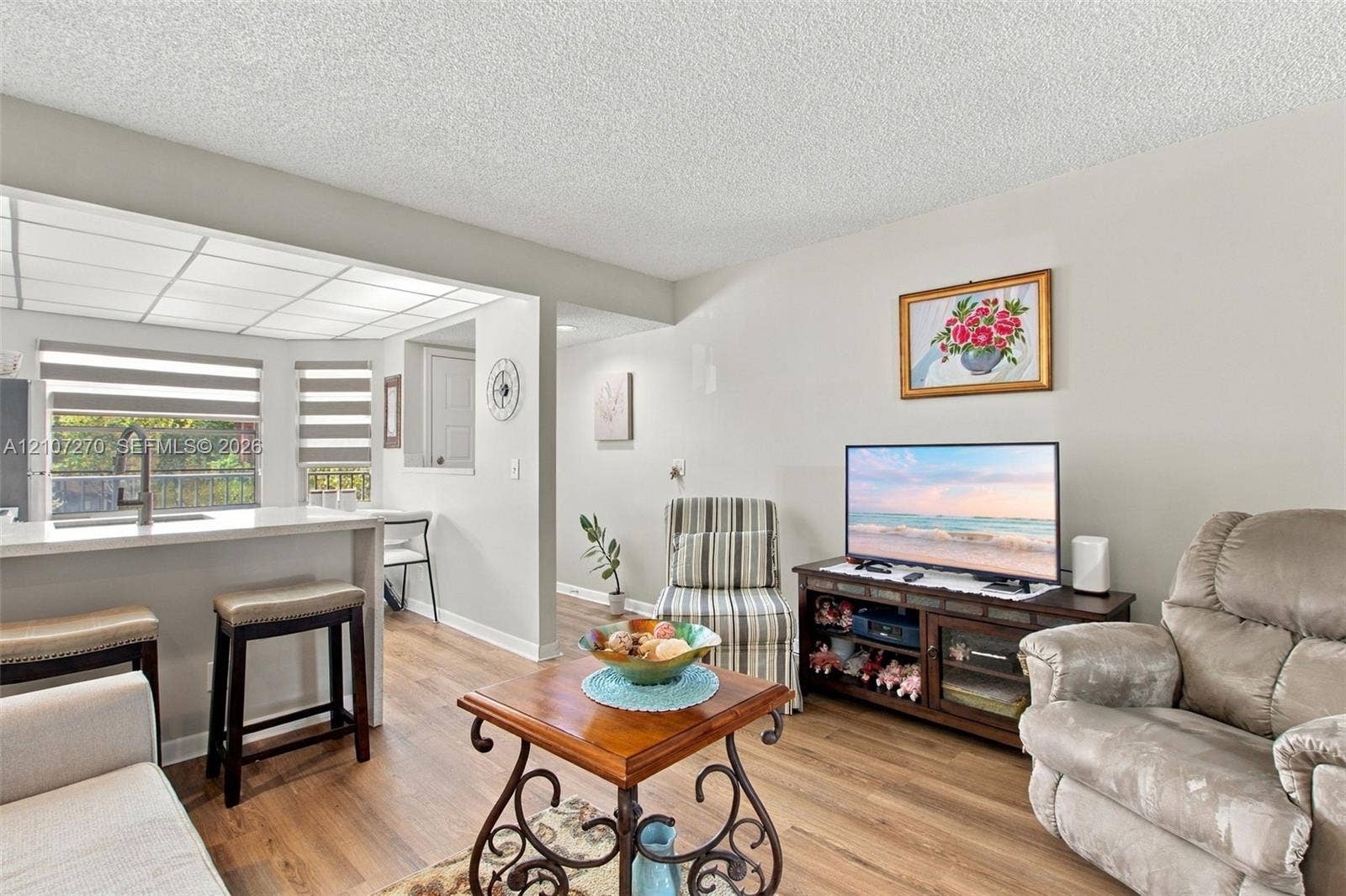 12501 SW 14th Street, #311R, Pembroke Pines, FL 33027 Open-concept interior featuring wood-finish flooring, a kitchen peninsula with a quartz countertop, and recessed ceiling panels with integrated lighting