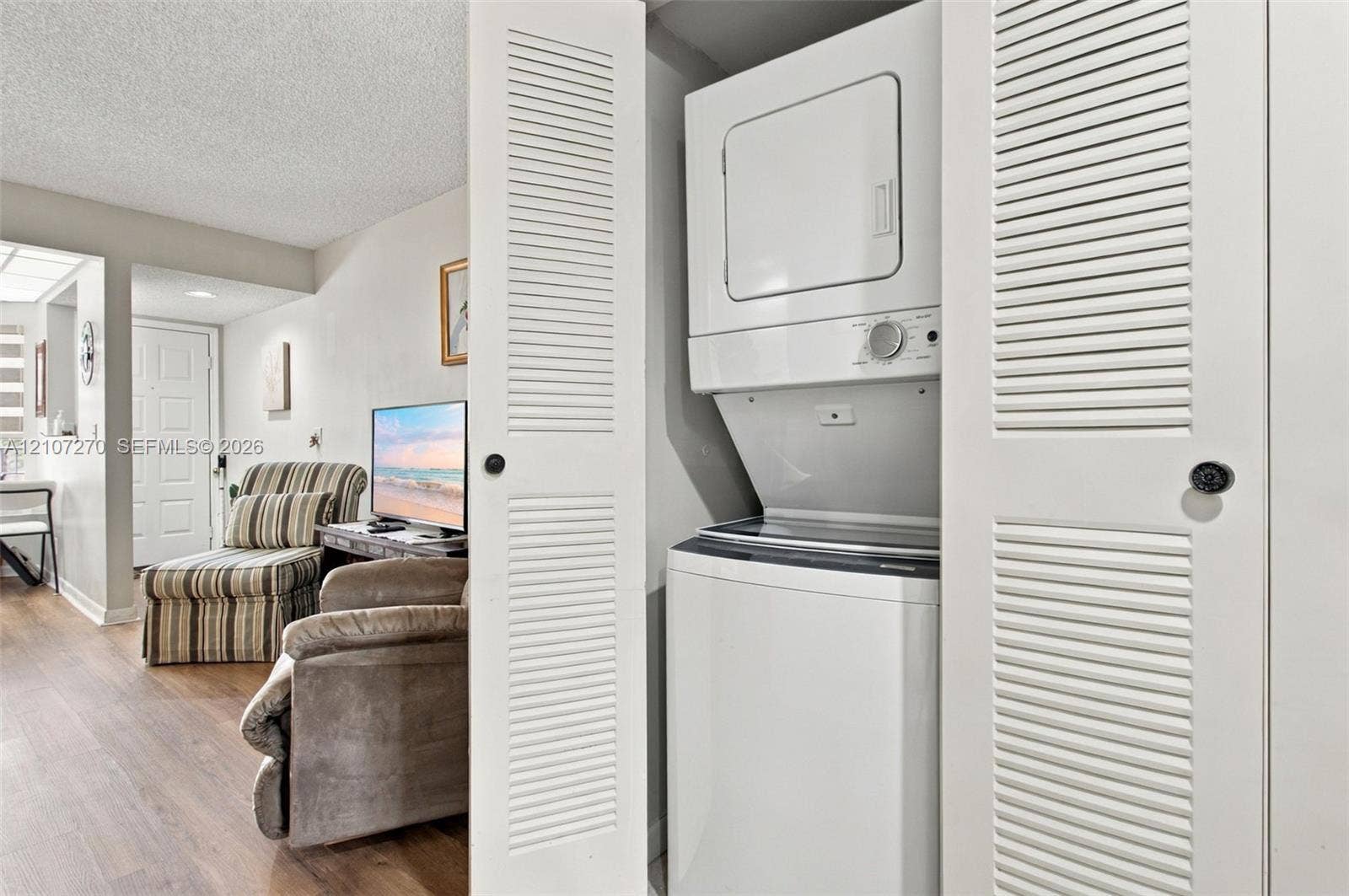 12501 SW 14th Street, #311R, Pembroke Pines, FL 33027 Laundry closet featuring louvered bifold doors and a stacked washer and dryer unit