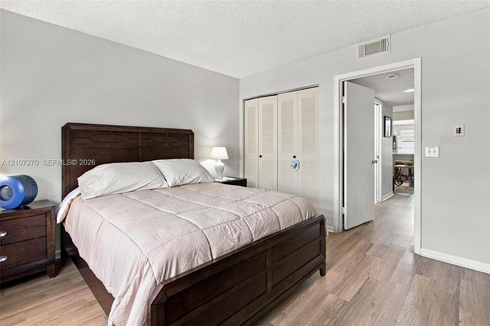 12501 SW 14th Street, #311R, Pembroke Pines, FL 33027 Bedroom featuring wood-finish flooring, neutral wall paint, and built-in louvered-door closets