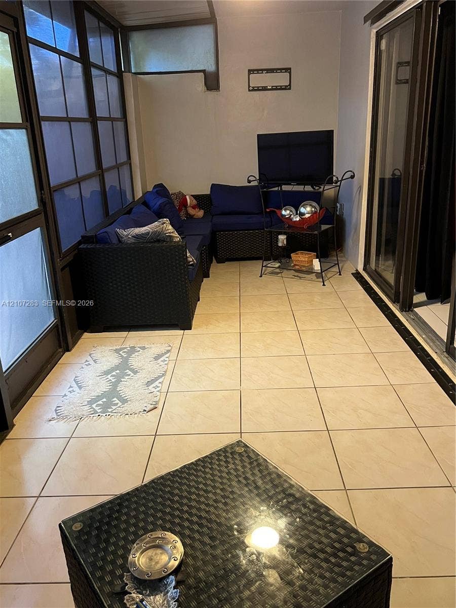 3301 Raleigh Street, #4E, Hollywood, FL 33021 Enclosed sunroom featuring large-format tile flooring, multi-pane floor-to-ceiling windows, and sliding glass door access