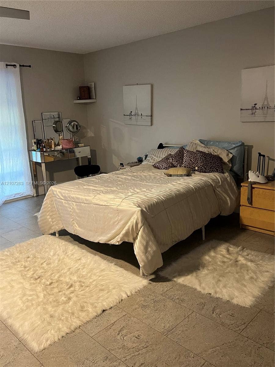 3301 Raleigh Street, #4E, Hollywood, FL 33021 Neutral-toned room featuring large-format ceramic tile flooring, a wall-mounted floating display shelf, and glass sliding door entry