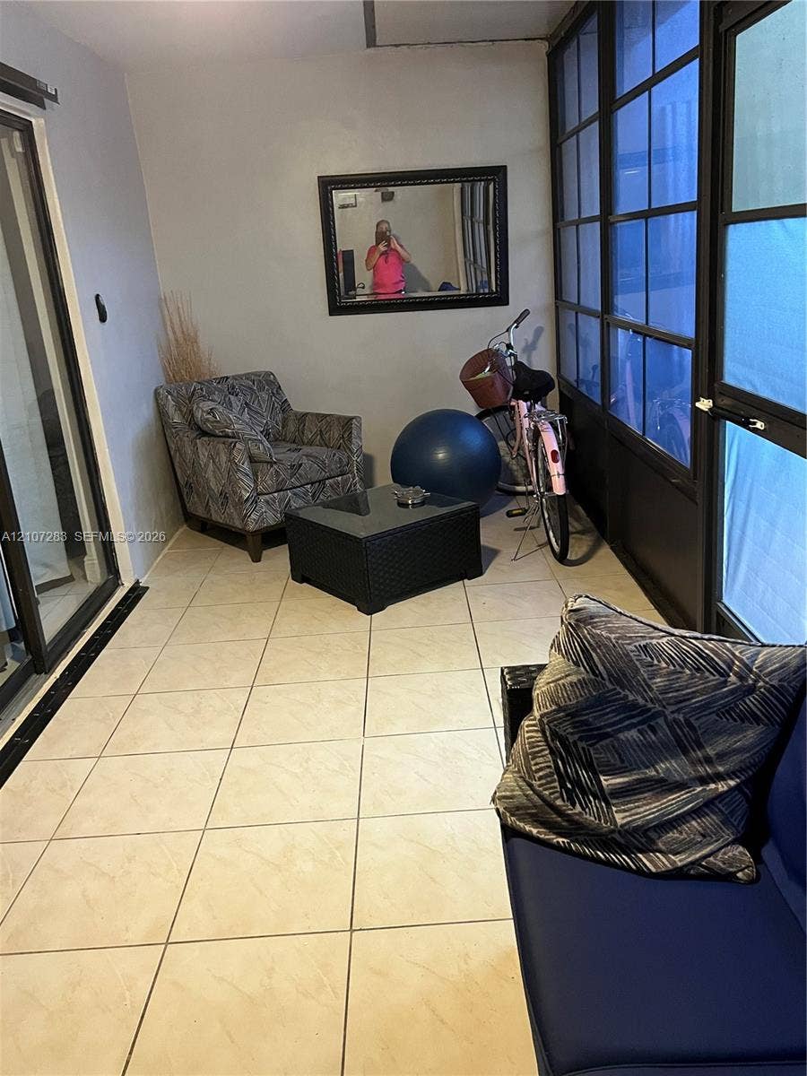 3301 Raleigh Street, #4E, Hollywood, FL 33021 Enclosed porch featuring large-format ceramic floor tiles, multi-pane floor-to-ceiling windows with black framing, and sliding glass entry door