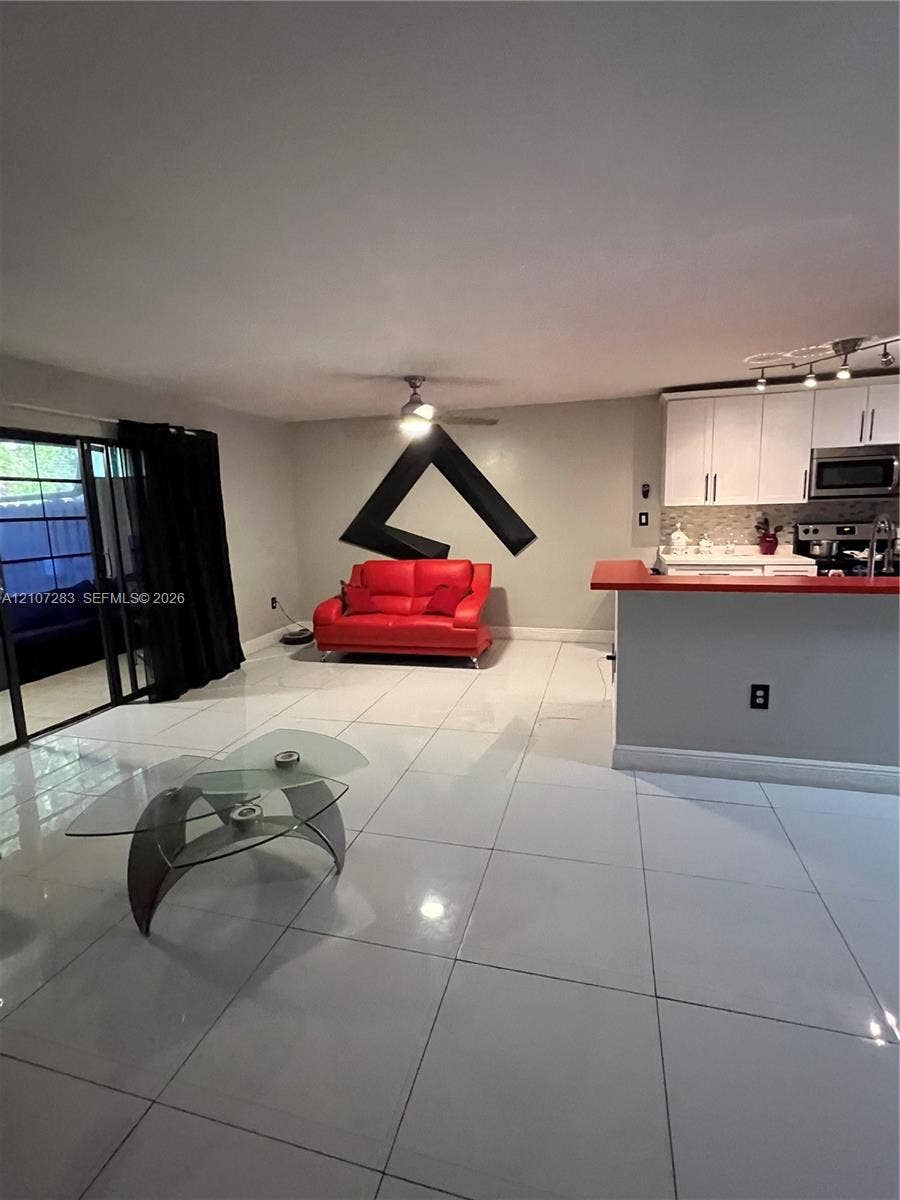 3301 Raleigh Street, #4E, Hollywood, FL 33021 Large format tile flooring, white cabinetry, integrated peninsula with red countertop, and sliding glass door with dark frame