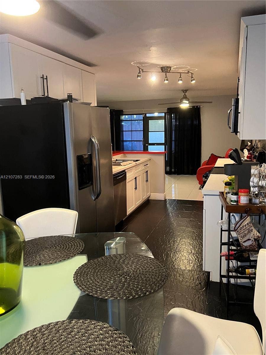3301 Raleigh Street, #4E, Hollywood, FL 33021 Kitchen featuring white cabinetry, stainless steel appliances, dark tile flooring, track lighting, and a multi-pane glass door