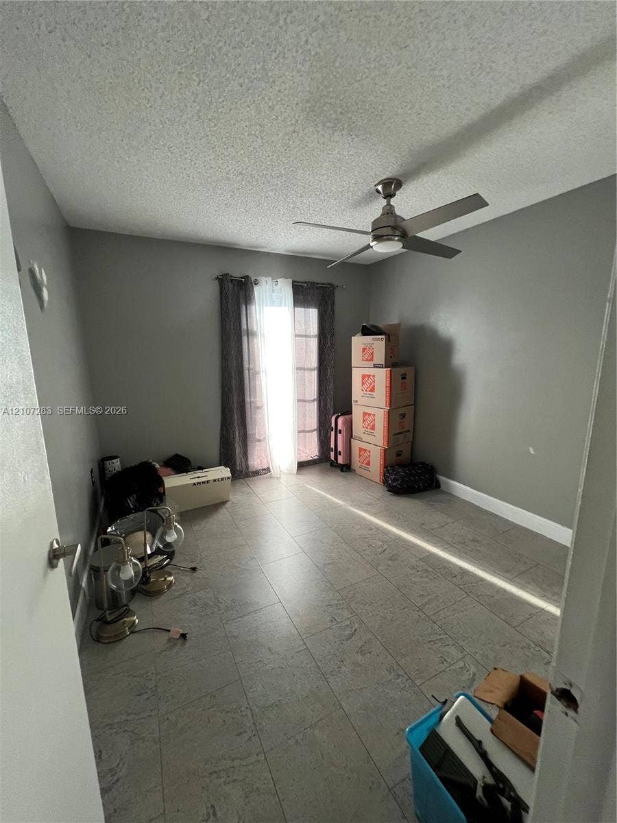 3301 Raleigh Street, #4E, Hollywood, FL 33021 Neutral-toned interior room featuring large-format tile flooring, a brushed metal ceiling fan, and sliding glass doors