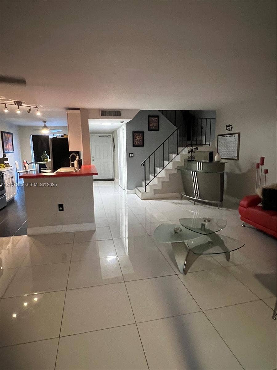 3301 Raleigh Street, #4E, Hollywood, FL 33021 Large-format porcelain tile flooring, breakfast bar with a solid surface countertop, and a staircase featuring metal railings