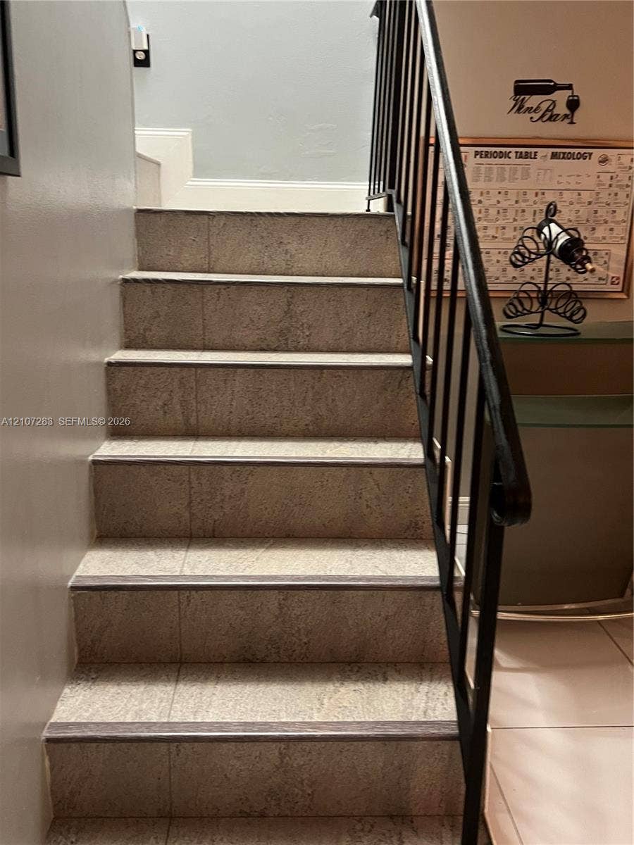 3301 Raleigh Street, #4E, Hollywood, FL 33021 Staircase featuring stone-textured treads, dark metal railings, and neutral wall tones