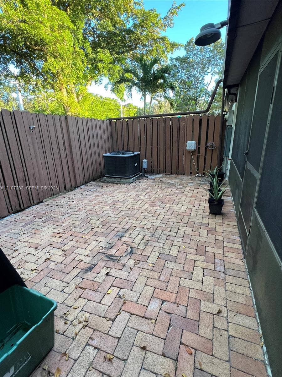 3301 Raleigh Street, #4E, Hollywood, FL 33021 Private patio featuring herringbone-patterned brick pavers and a tall wood-slat privacy fence