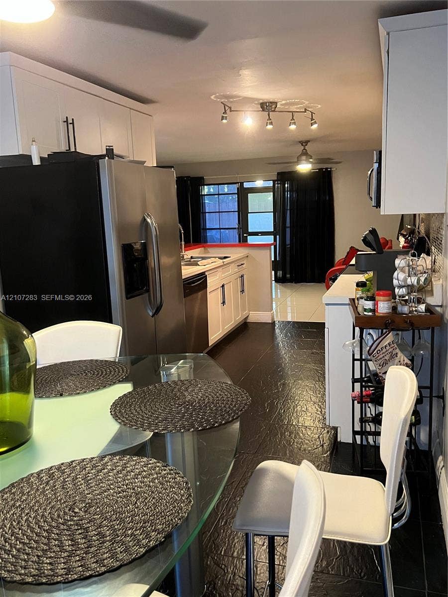 3301 Raleigh Street, #4E, Hollywood, FL 33021 Kitchen featuring white shaker-style cabinetry, stainless steel appliances, dark tile flooring, and a multi-directional track lighting fixture