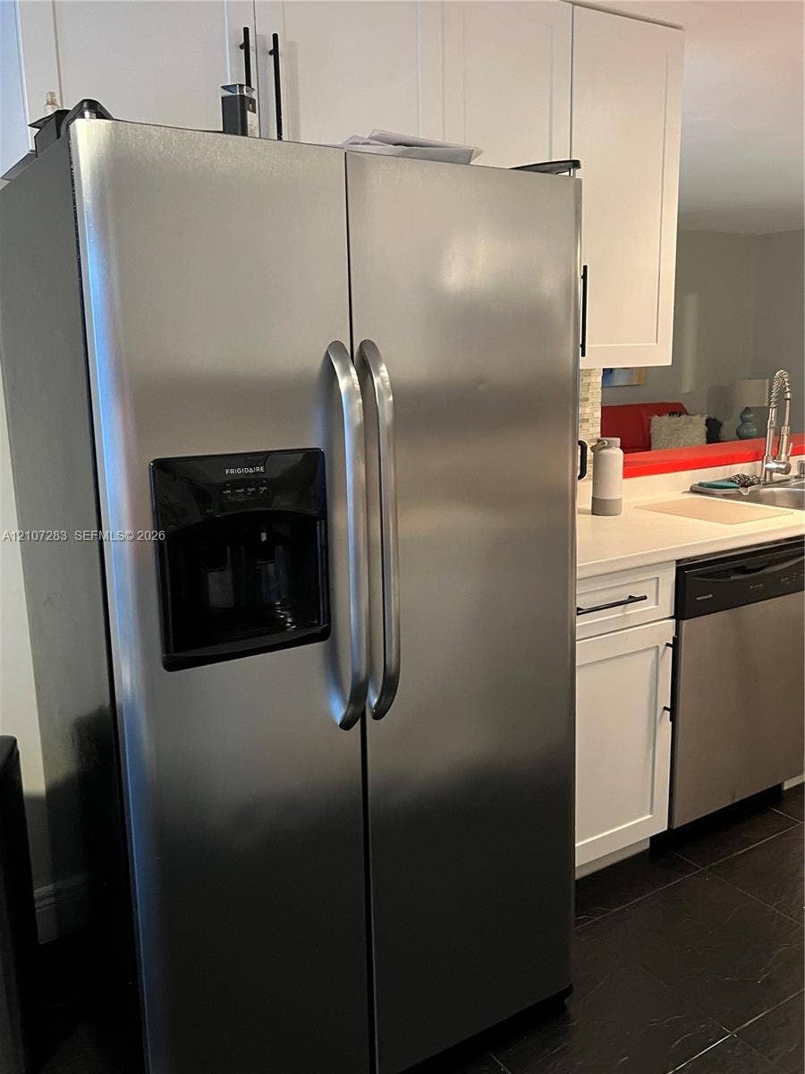 3301 Raleigh Street, #4E, Hollywood, FL 33021 Stainless steel side-by-side refrigerator, white shaker-style cabinetry with matte black hardware, stone-finish countertops, undermount sink, and dark tile flooring