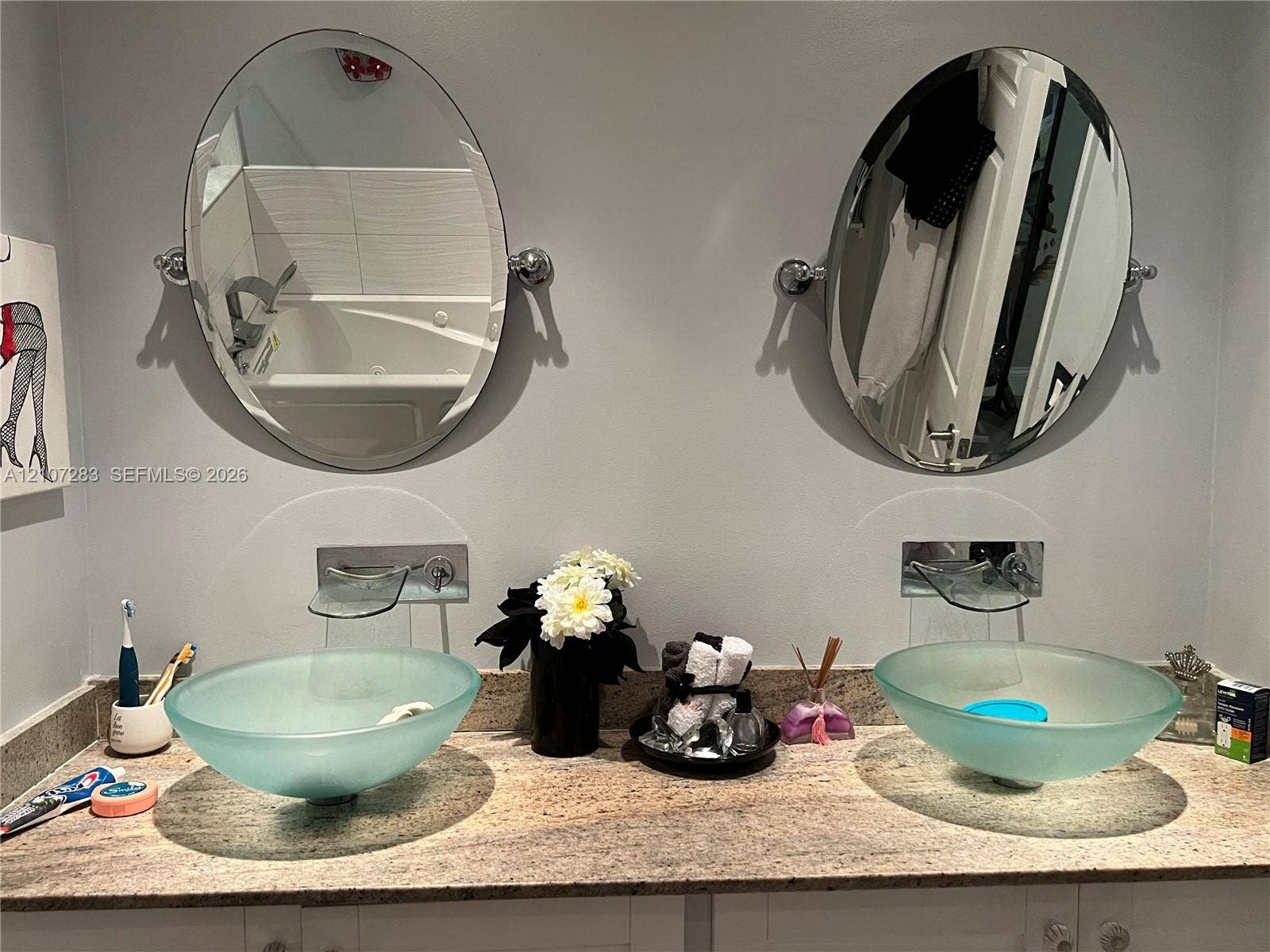 3301 Raleigh Street, #4E, Hollywood, FL 33021 Dual vanity featuring frosted glass vessel sinks, stone countertop, wall-mounted faucets, and oval tilting mirrors