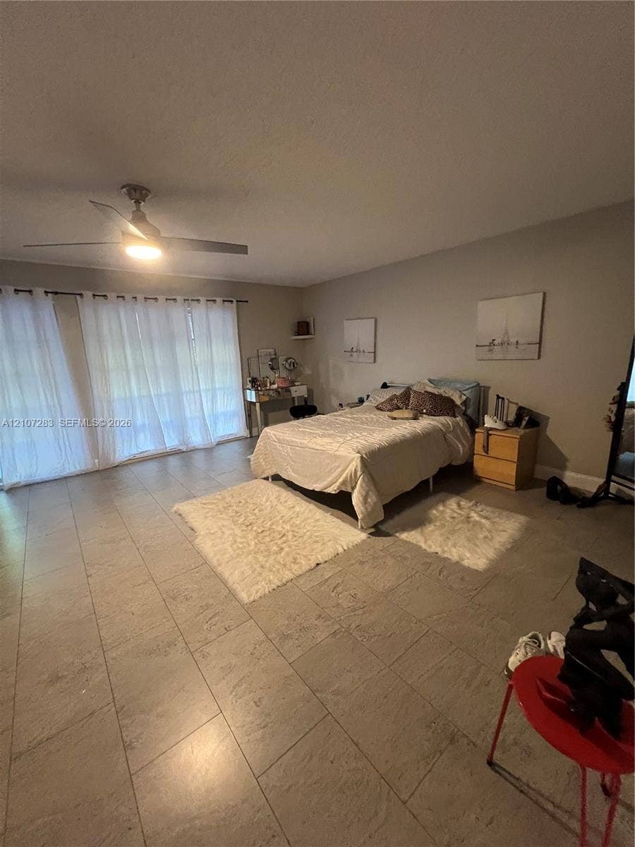 3301 Raleigh Street, #4E, Hollywood, FL 33021 Neutral-toned ceramic tile flooring, large sliding glass door with integrated tracks, and a contemporary ceiling fan with integrated lighting
