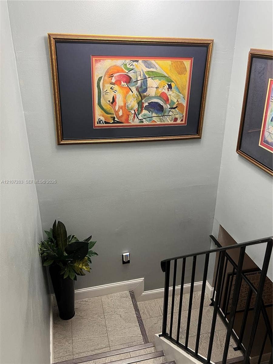 3301 Raleigh Street, #4E, Hollywood, FL 33021 Staircase featuring neutral-toned wall paint, stone-finish treads, and a matte black metal railing