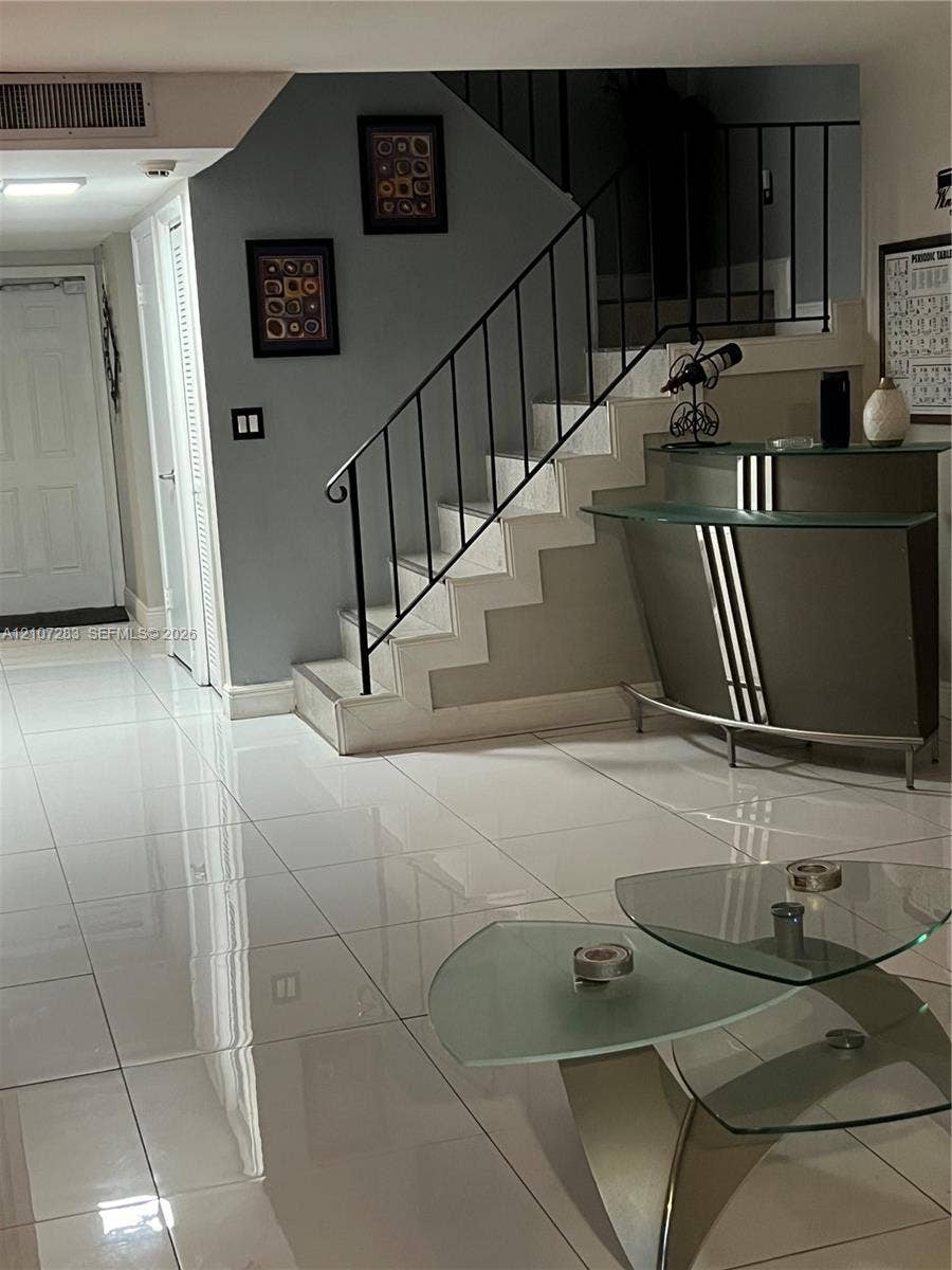 3301 Raleigh Street, #4E, Hollywood, FL 33021 Large-format polished tile flooring, staircase with a black metal railing, and crisp neutral wall finish