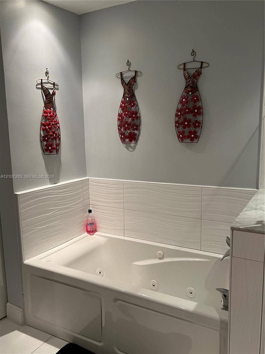 3301 Raleigh Street, #4E, Hollywood, FL 33021 Jetted soaking tub featuring a white surround and textured horizontal tile backsplash