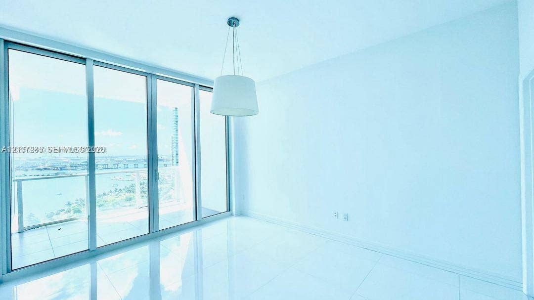 2020 N Bayshore Drive, #2102, Miami, FL 33137 Floor-to-ceiling glass sliding doors, polished tile flooring, pendant lighting, and an expansive balcony