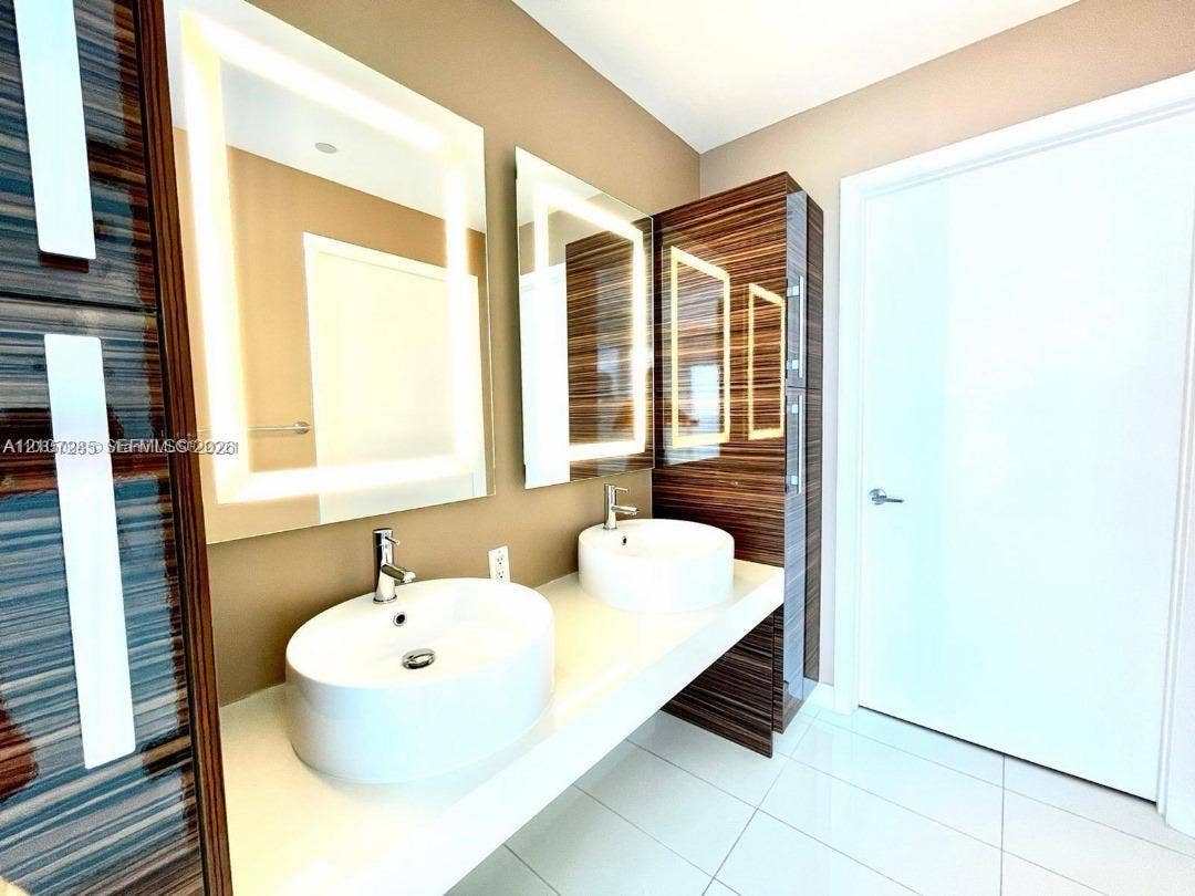 2020 N Bayshore Drive, #2102, Miami, FL 33137 Floating double vanity featuring rectangular vessel sinks, quartz countertop, integrated wood-finish cabinetry, and back-lit mirrors with chrome faucets