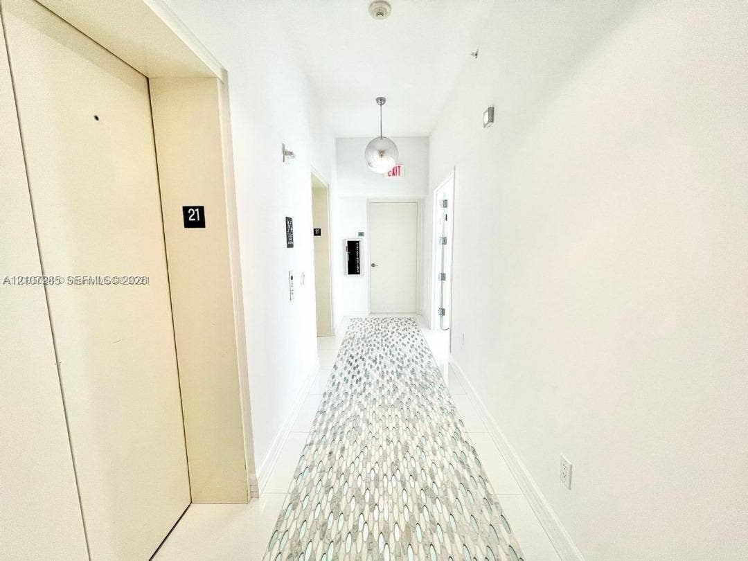 2020 N Bayshore Drive, #2102, Miami, FL 33137 Hallway featuring neutral-toned walls, polished tile flooring, patterned runner carpet, and a spherical pendant light fixture