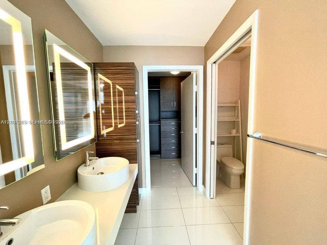 2020 N Bayshore Drive, #2102, Miami, FL 33137 Dual floating vanity with rectangular vessel sinks, LED-backlit mirrors, wood-finish cabinetry, and porcelain tile flooring