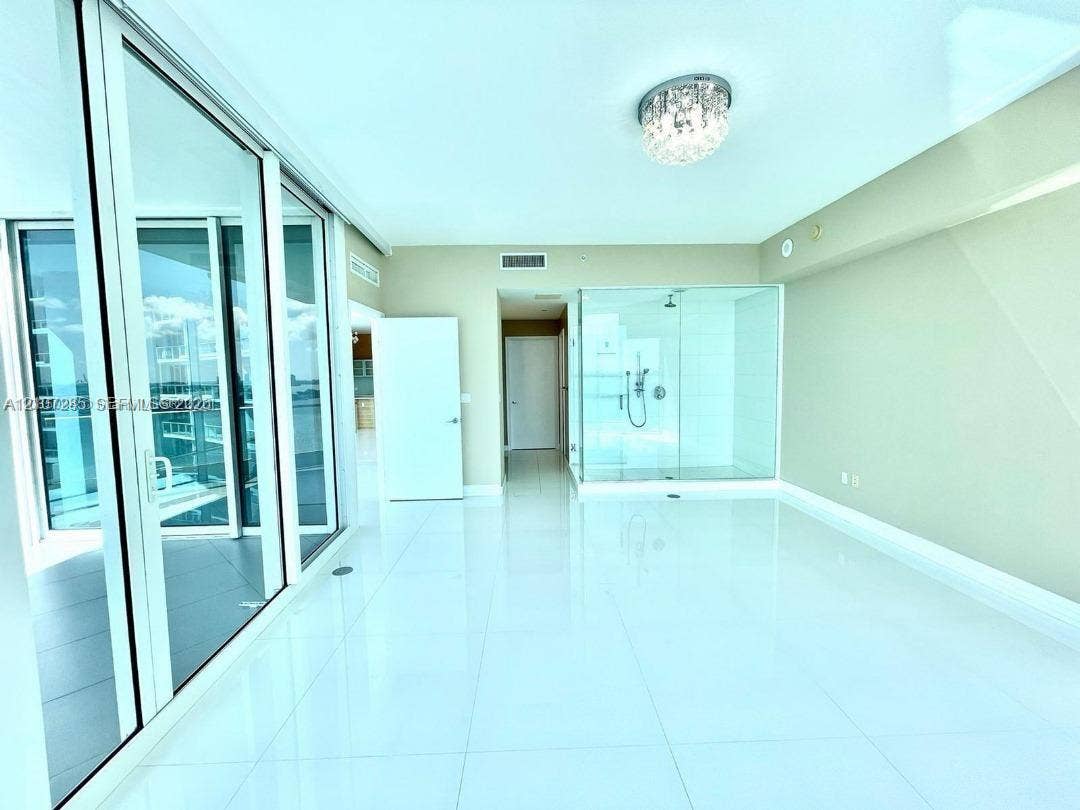 2020 N Bayshore Drive, #2102, Miami, FL 33137 Polished tile flooring, floor-to-ceiling glass sliding doors, glass-enclosed shower, and decorative crystal flush-mount lighting