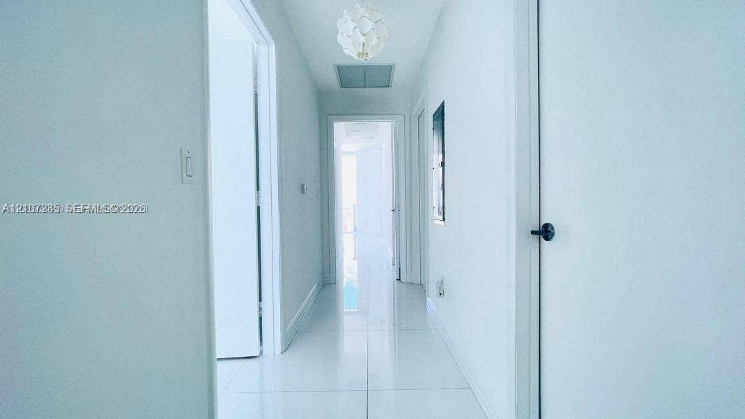 2020 N Bayshore Drive, #2102, Miami, FL 33137 Hallway featuring high-gloss tile flooring, white interior doors with matte black hardware, and a contemporary spherical pendant light fixture