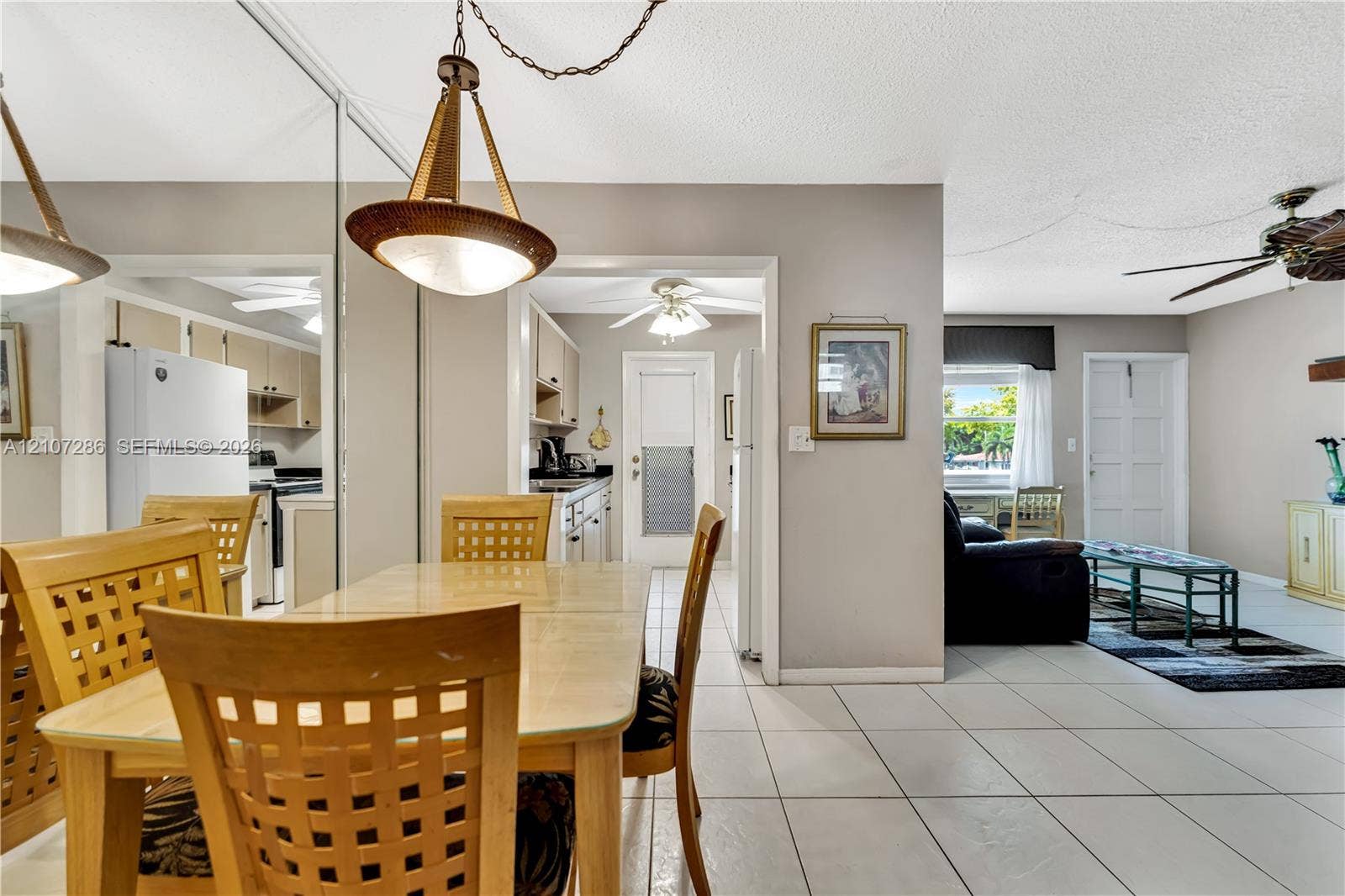 2458 Polk Street, #206, Hollywood, FL 33020 Open-concept interior featuring oversized wall mirrors, neutral tile flooring, a multi-light pendant fixture, ceiling fans, and a classic paneled exterior door