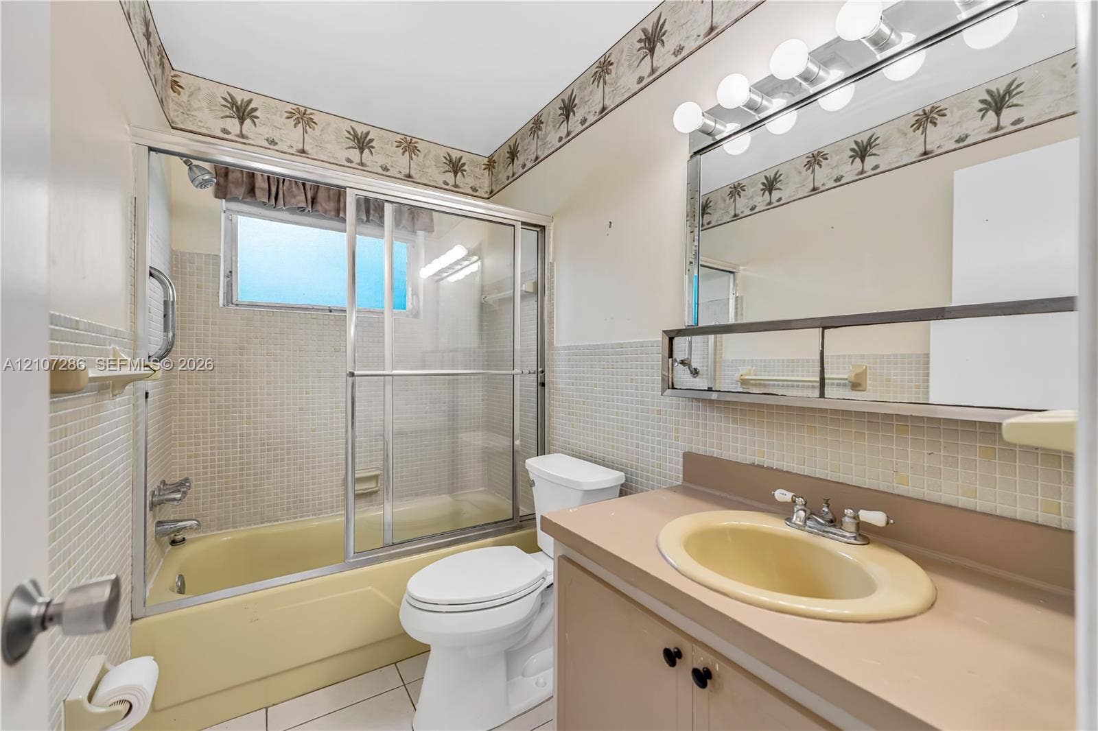 2458 Polk Street, #206, Hollywood, FL 33020 Bathroom featuring a shower and tub combination with sliding glass doors, vanity with an integrated basin, wall-mounted mirror, and tile wall surfacing