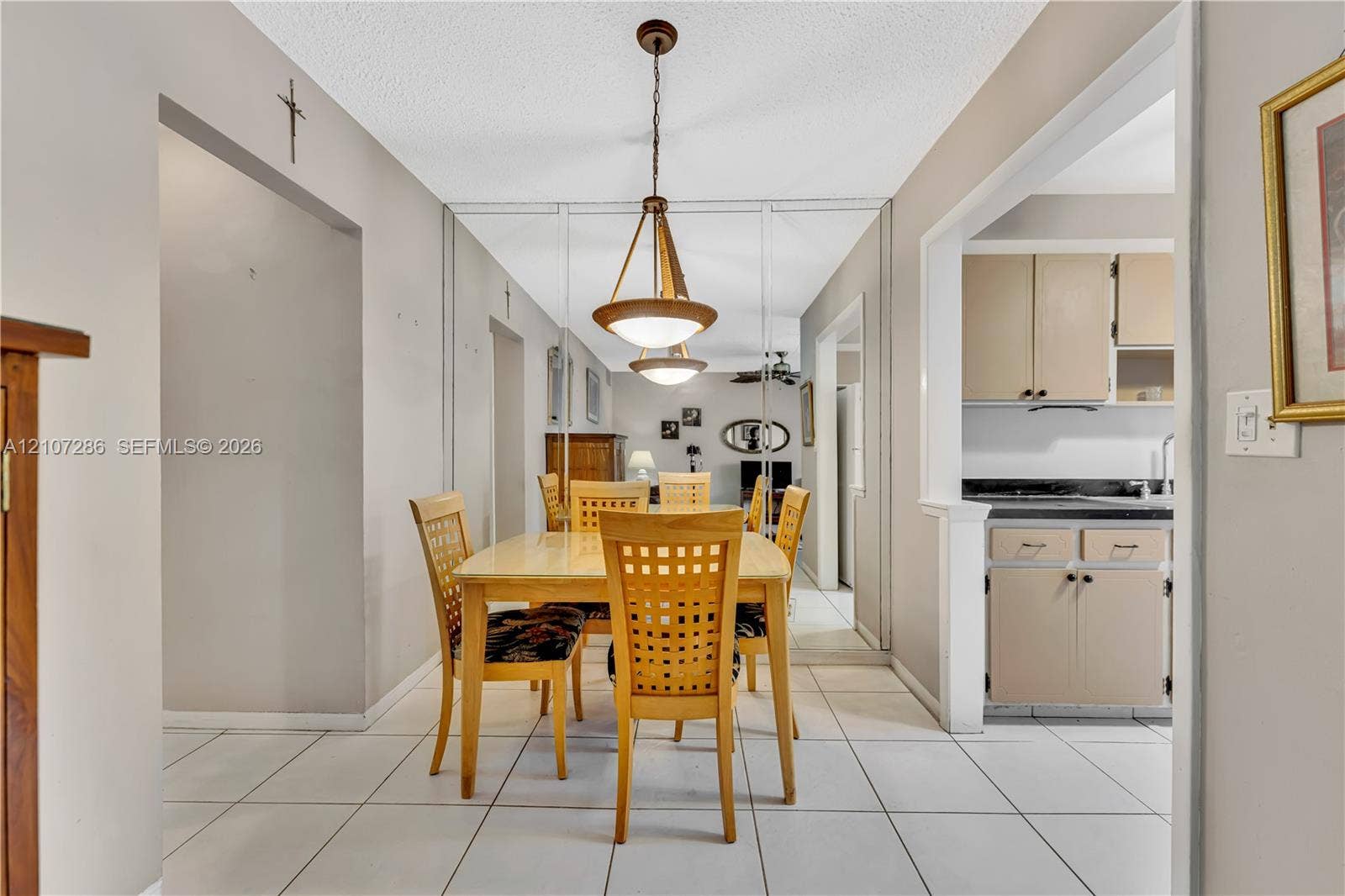 2458 Polk Street, #206, Hollywood, FL 33020 Dining area featuring ceramic tile flooring, floor-to-ceiling mirrored wall panels, and a tiered pendant light fixture